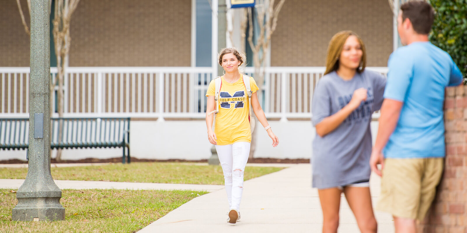 Student strolls leisurely through sunlit campus.