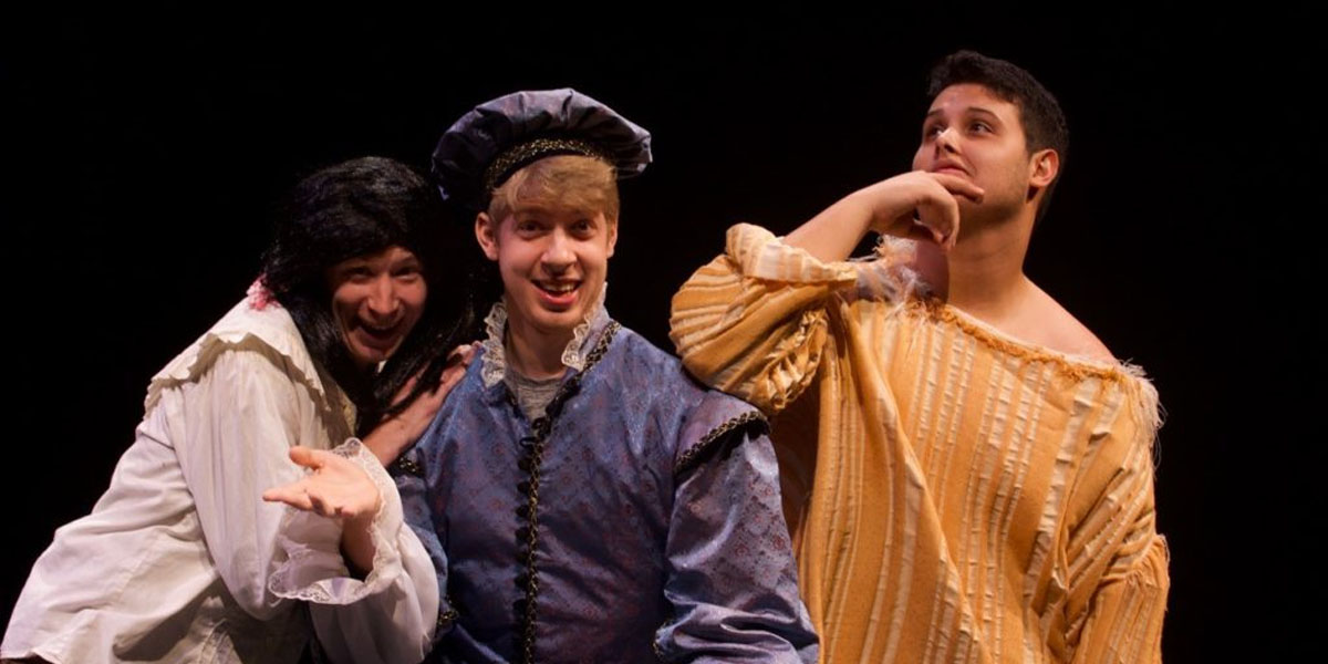 Three actors in medieval costumes strike a humorous pose. They appear as if they can't help laughing at themselves.
