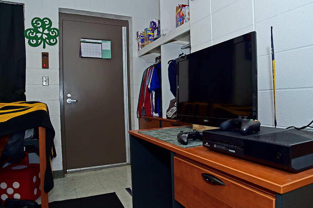 TV and Xbox sit on a desk in a dorm room.