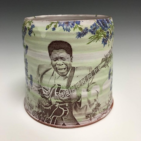 Legendary blues artist B.B. King playing his guitar on front of ceramic pottery