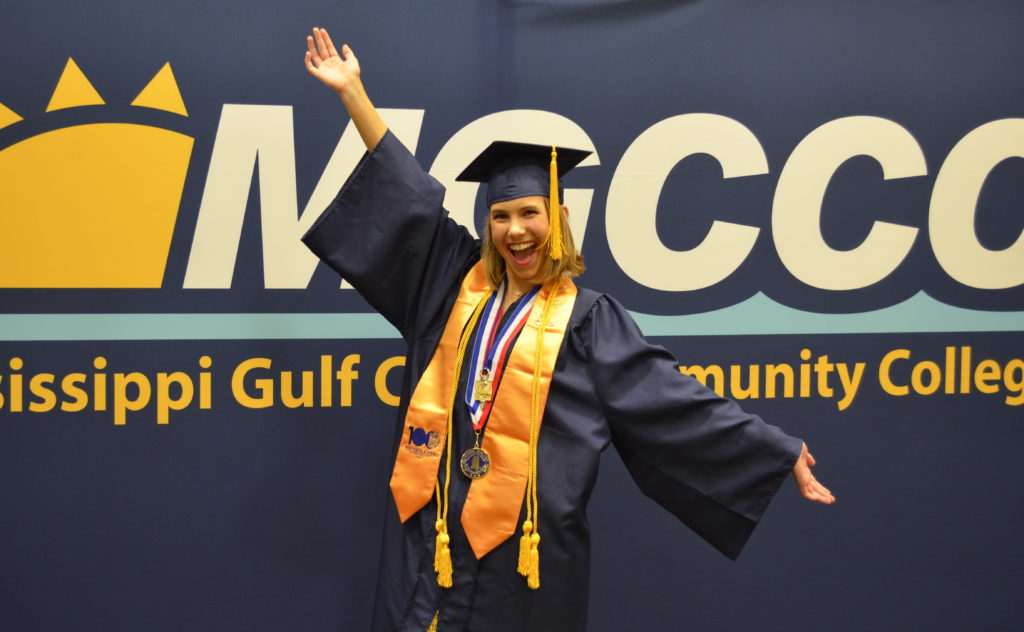 Faith Marshall in cap and gown in front of an MGCCC banner