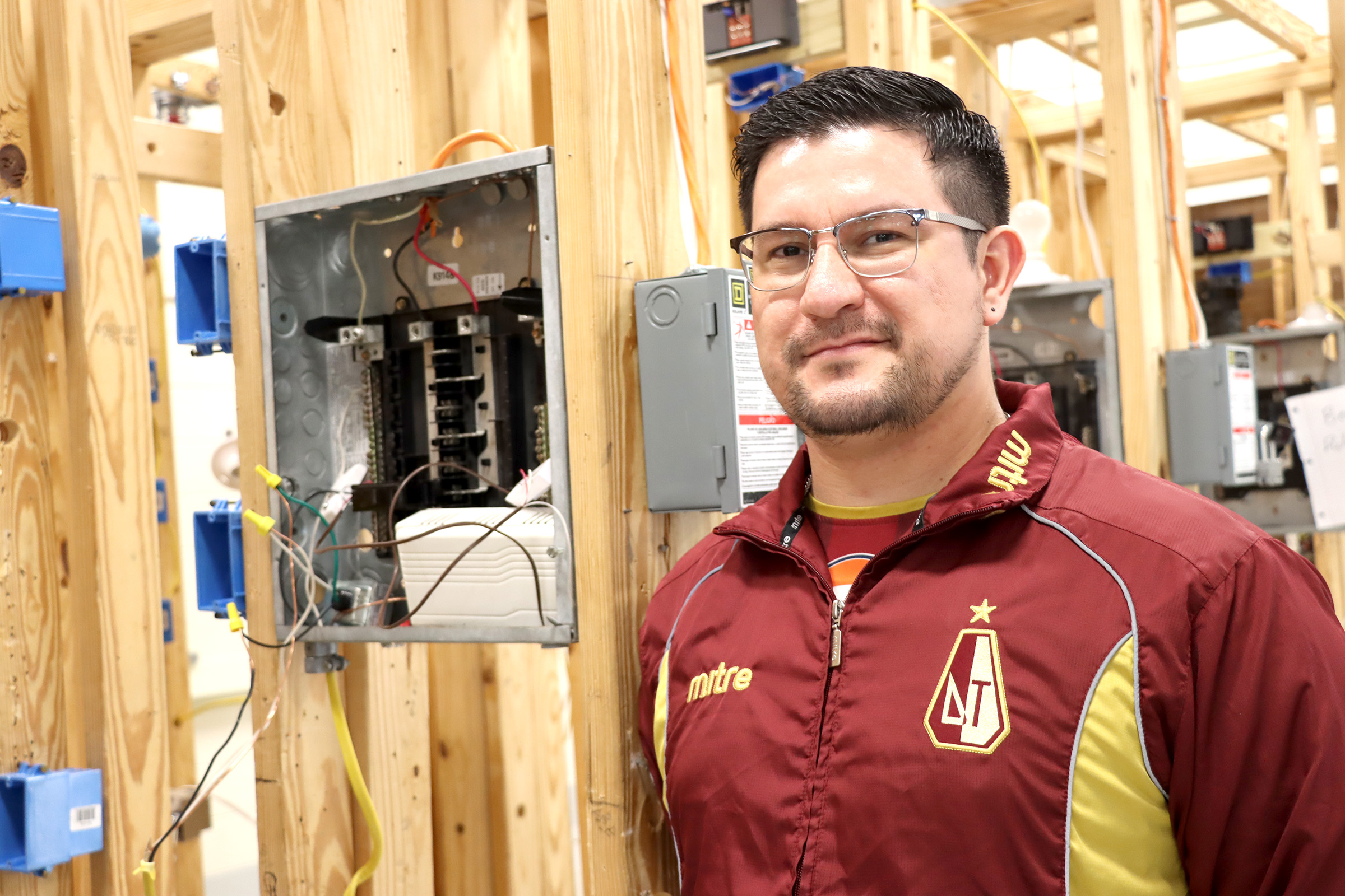 Giovanni Pena is a student in the Electrical Tech Program at Harrison County Campus. The building behind him is a project that students are working on to give them a feel for wiring a whole house.