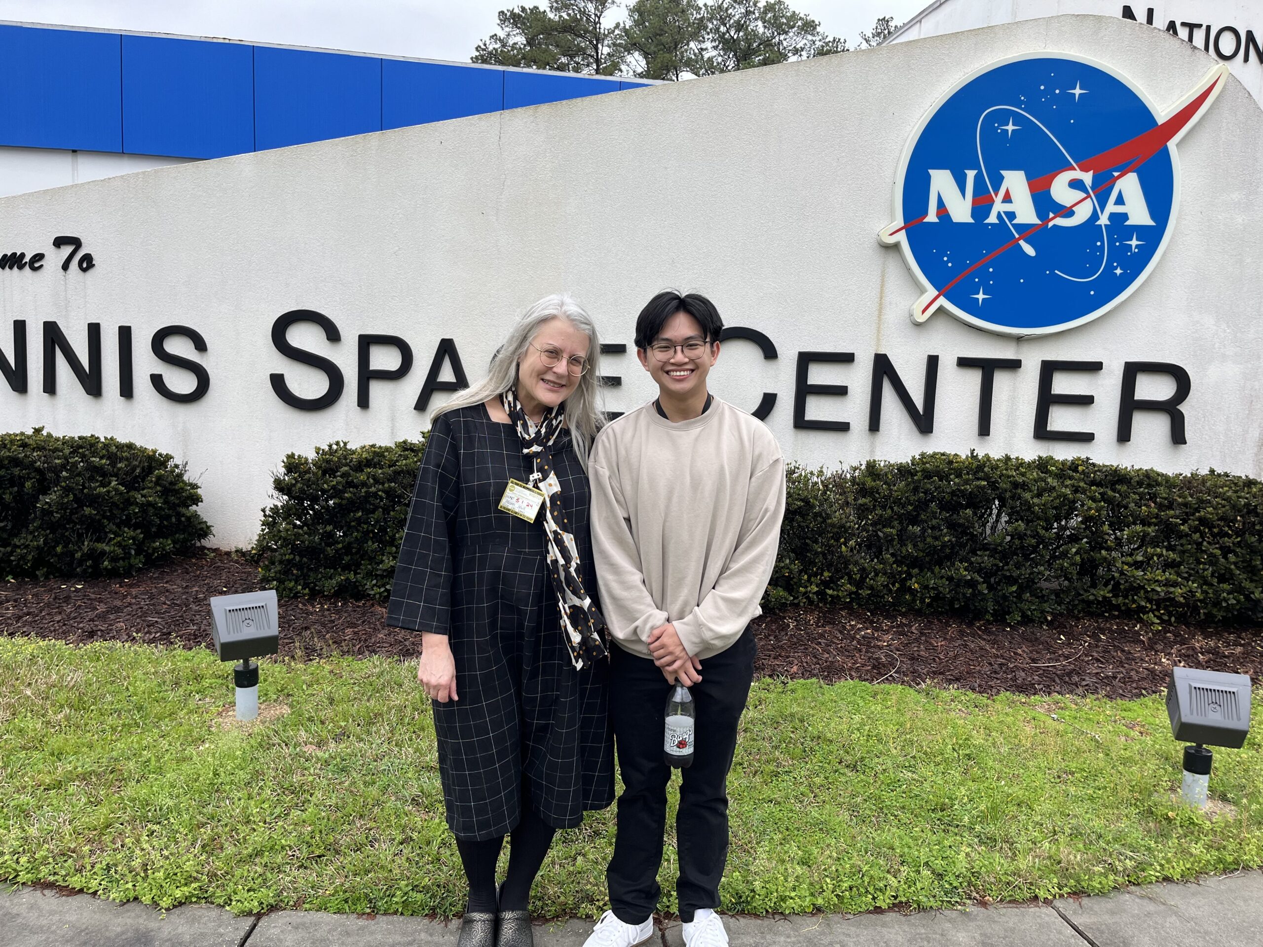 Antoine Nguyen with MGCCC instructor Allison Mull in front of the sign at Stennis Space Center.