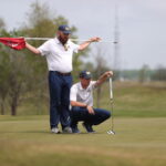 Coach Brad Thornton helping Will Burnham on the golf links.