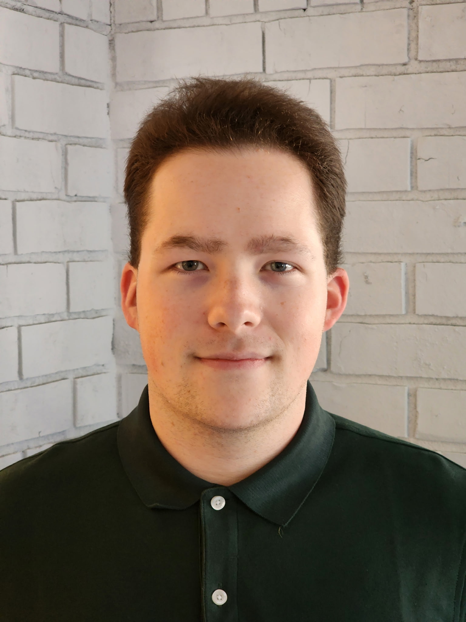 Portrait of Aiden Graves standing in front of a brick wall