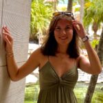 Hannah Sykes portrait in a green dress with sunglasses on the top of her head