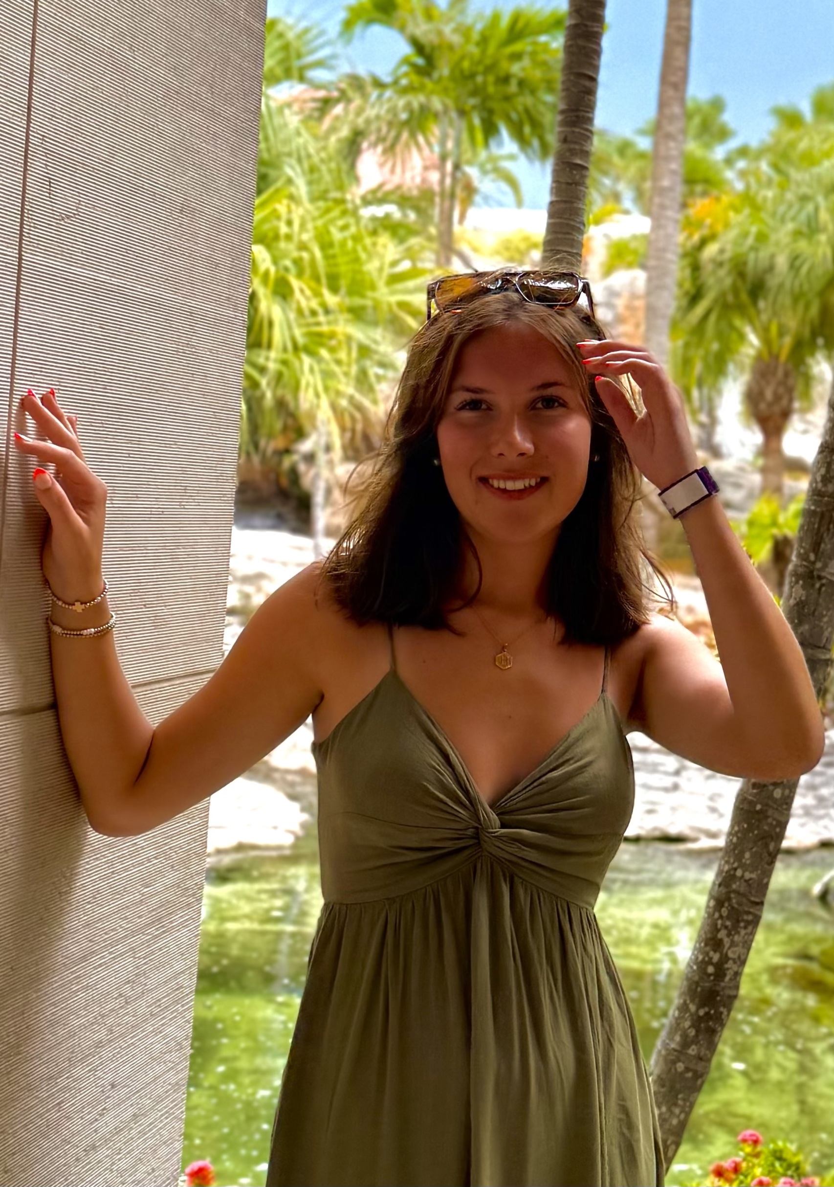 Hannah Sykes portrait in a green dress with sunglasses on the top of her head