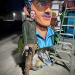 Jackson Jones standing in front of a Mardi Gras float figurehead with a paint spray gun.