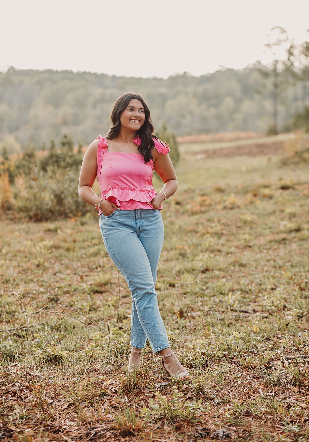 Rubi Ramirez standing in a field with a pink shirt and blue jeans.