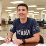 Jon Hayden working in the LRC at the JC Campus. Student at desk with blue navy shirt on.