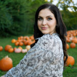 Sara Fisher sitting in a pumpkin field