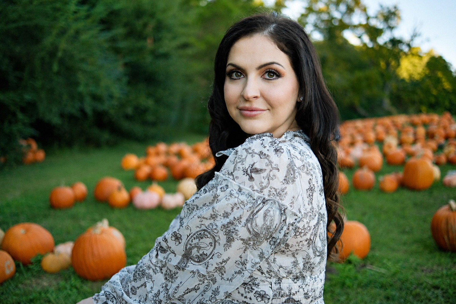 Sara Fisher sitting in a pumpkin field
